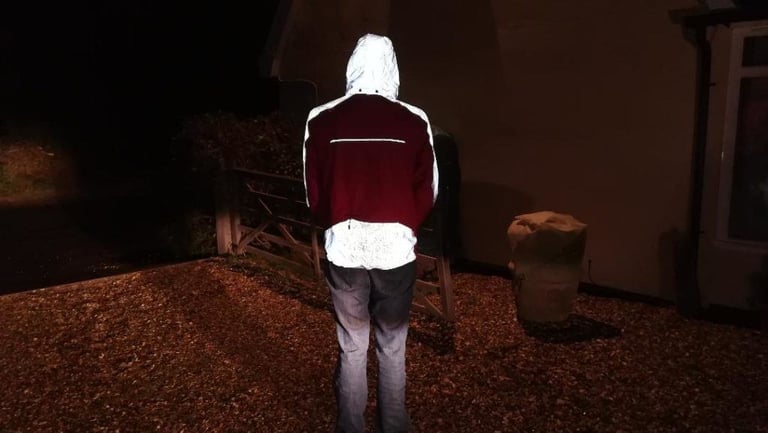 Hood up on the Altura Nightvision Thunderstorm Jacket at night, seen from behind, the hood and back panel reflecting white.