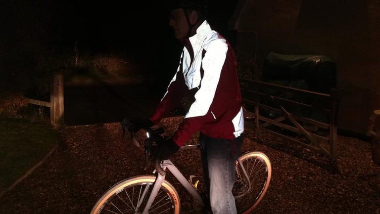 Rider on a bike at night, the Altura Nightvision jacket's reflective panels lit up across the shoulders and upper arms.
