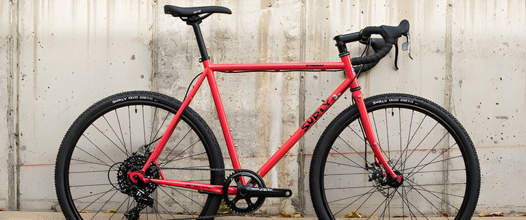 Complete Surly Straggler in Salmon Candy Red with drop bars and a 1x drivetrain, side view.