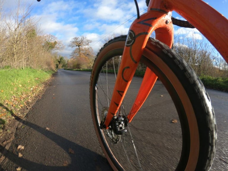 Tanwall WTB Sendero on the front wheel of the Mason Bokeh, rolling along a quiet tarmac lane under blue sky.