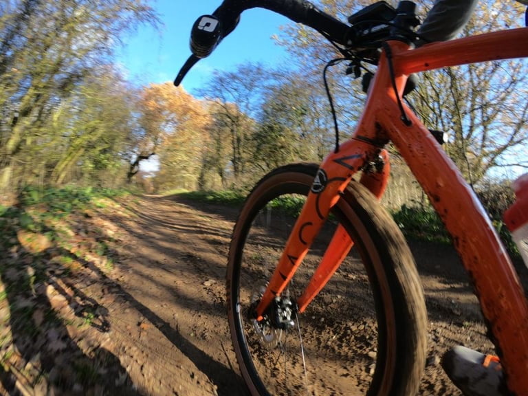 Front wheel of the Mason Bokeh on a Sendero tyre, riding a muddy dirt track through autumn woodland.