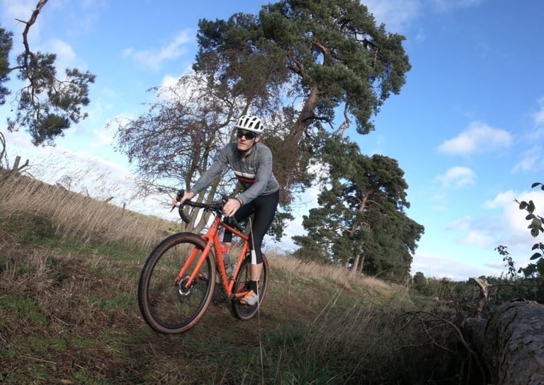 Rider leaning the Mason Bokeh into a grassy bend on WTB Sendero tyres, pine trees and blue sky behind.