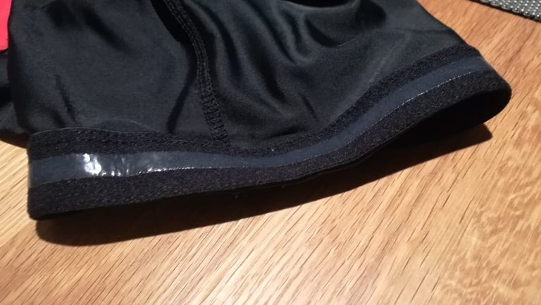 Leg gripper of the Alpkit Rhythm bibtights showing a single thin strip of silicone on a wooden table.