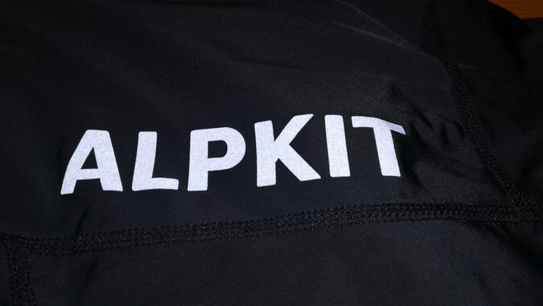 Reflective Alpkit lettering on the leg of the Rhythm 3/4 Bibtights, picked out in silver-white print.