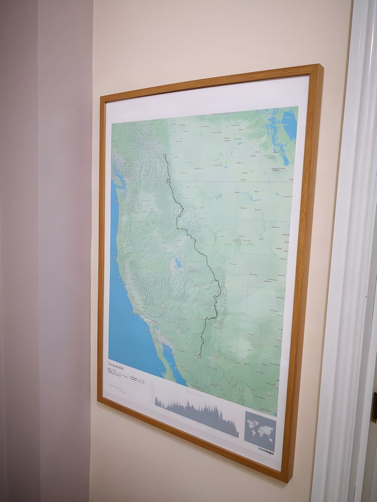 Framed Tracemaps print of the Tour Divide route down western North America hanging on a wall at home.