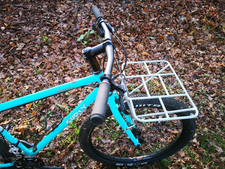 Silver Surly 24-Pack Rack over the front wheel of a turquoise Bridge Club, seen from behind the handlebars.