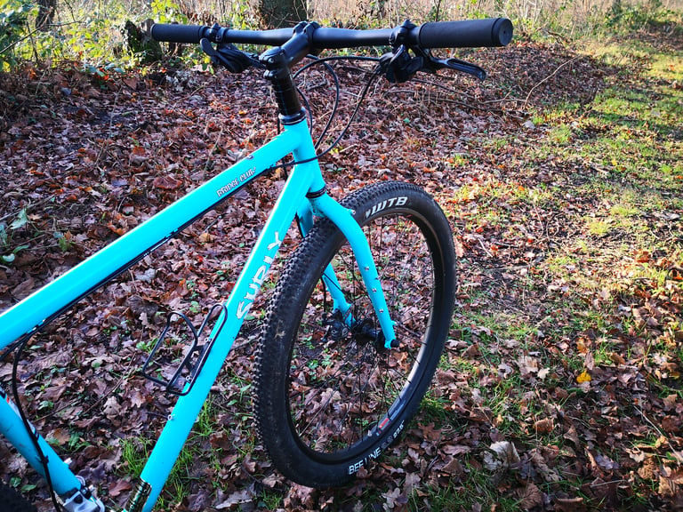 Surly Bridge Club front end from above: flat bars, stacked spacers, bottle cage and WTB Beeline front tyre on leaf litter.