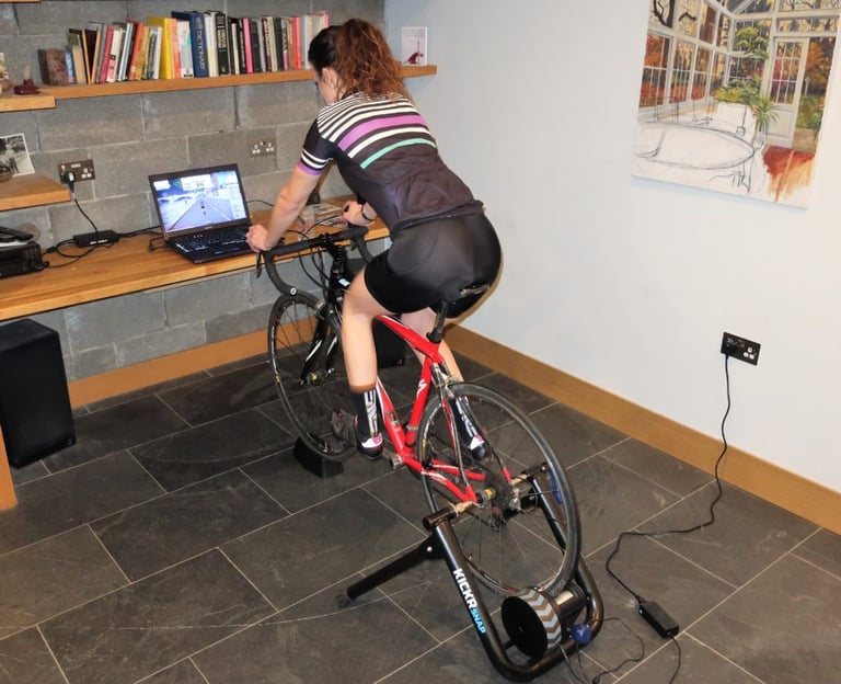 Rider pedals a Specialized road bike on the Wahoo KICKR Snap during testing, with Zwift running on the laptop ahead.