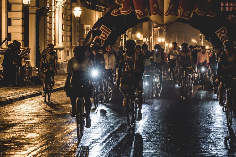 BikingMan Peru riders with lights on roll out at night beneath an inflatable start arch.