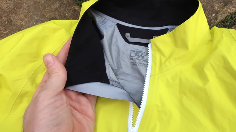 Collar of the 7Mesh Rebellion jacket folded back by hand to show the black brushed lining and the size label.