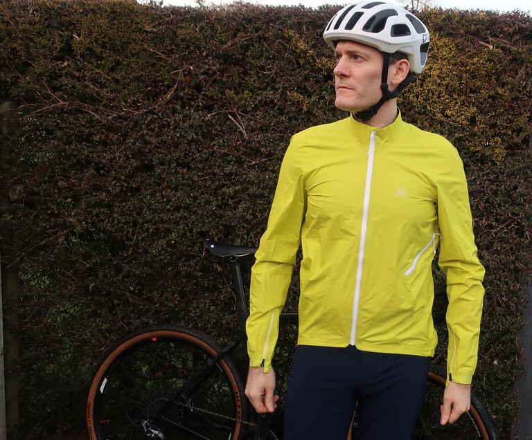 7Mesh Rebellion jacket in Sulphur neon yellow laid flat on paving, with white zips and a grey lining.