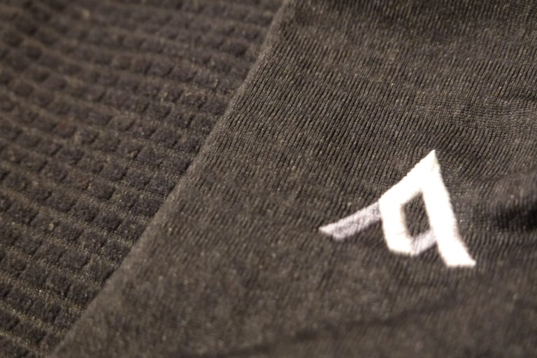 Close-up of the 7Mesh Mission Jersey's Polartec MicroGrid fleece, grid interior on the left and smooth exterior with logo.