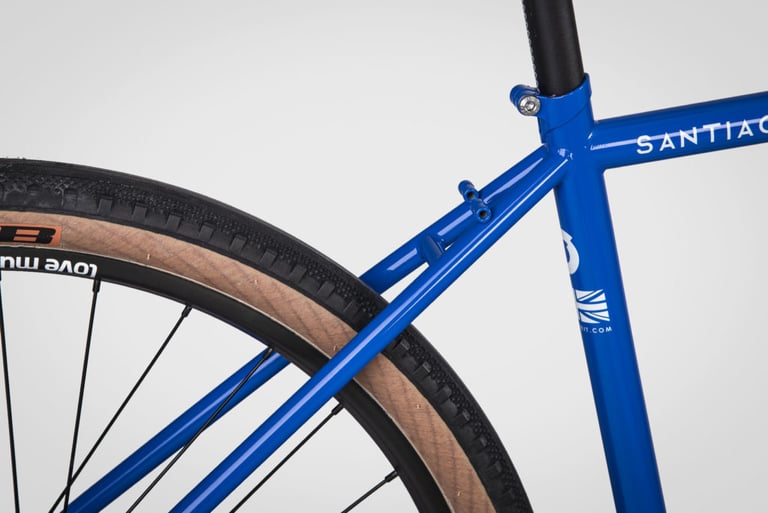 Close-up of the blue Sonder Santiago seat tube, seatstays and integrated seat collar above a tan-wall tyre.