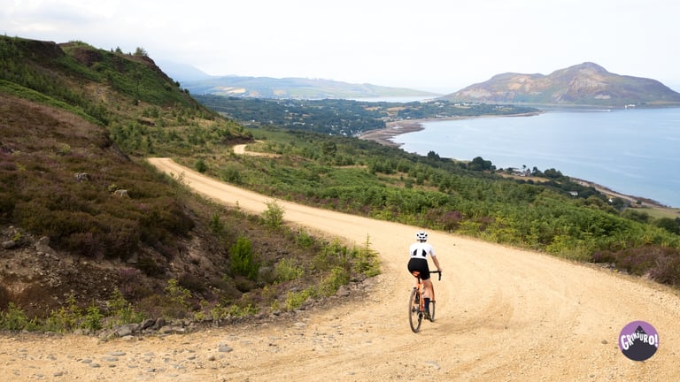 Grinduro Scotland rider on a sandy gravel road winding above the sea on the Isle of Arran.