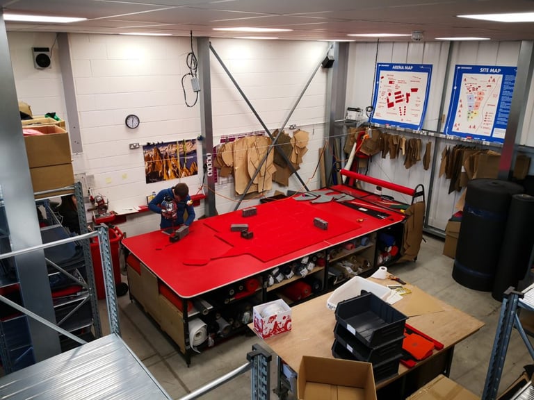 Overhead view of the red cutting table and hanging cardboard patterns in Alpkit's bag-making room at Nottingham HQ.