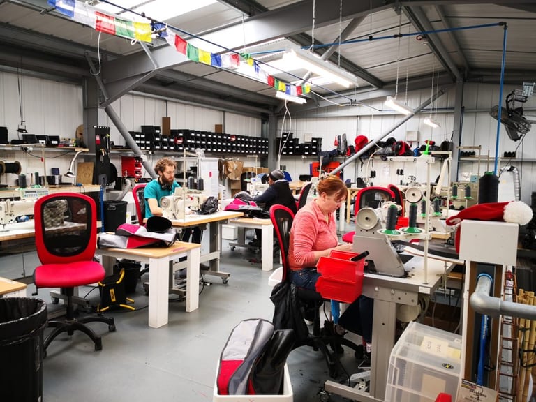 Alpkit staff sewing custom bags at machines in the Nottingham HQ production room.