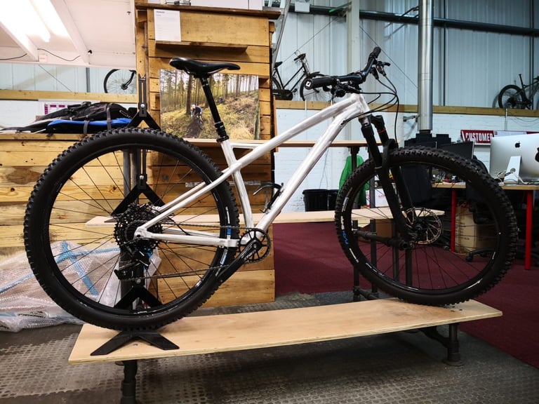 Prototype alloy Sonder Signal hardtail in raw unpainted aluminium on a wooden bench at Alpkit HQ.