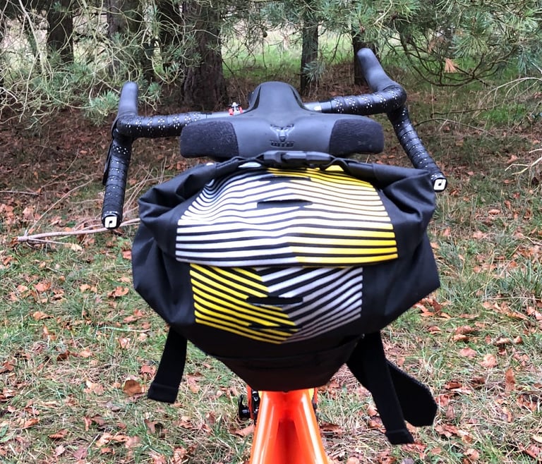 Rear view of the Apidura Racing Saddle Pack with its reflective yellow and white pattern, behind the handlebars.