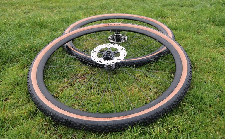 Sharp Precision gravel wheel pair with DT Swiss 350 hubs and WTB Resolute 700x42 tan-wall tyres lying flat on grass.
