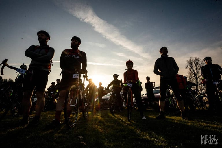 Riders with number boards stand with their bikes in low sun before the start of Yorkshire True Grit Dark Skies.