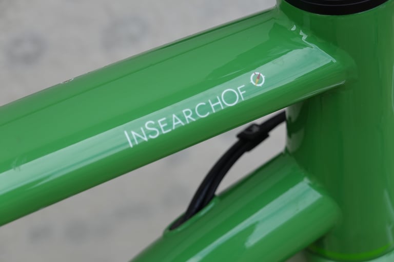 Close-up of the white InSearchOf logo painted on the green top tube of the Mason ISO.