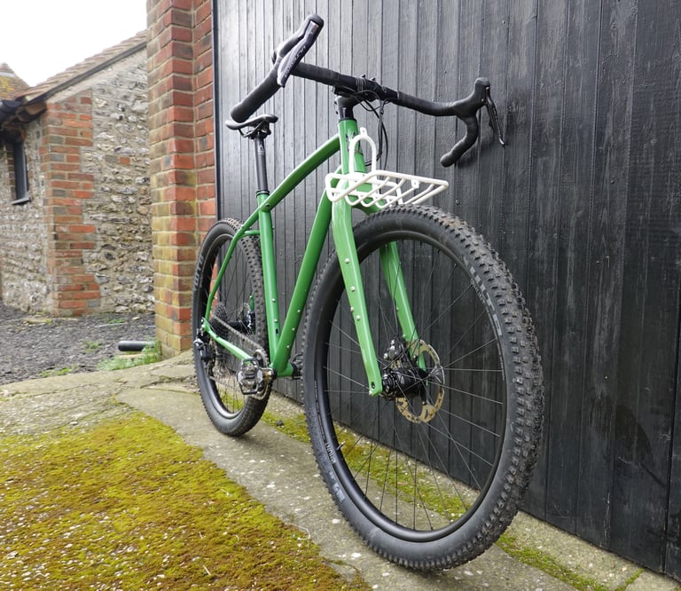 Mason ISO leaning on a black barn door, with a white 3D-printed prototype front rack and chunky 29er tyres.