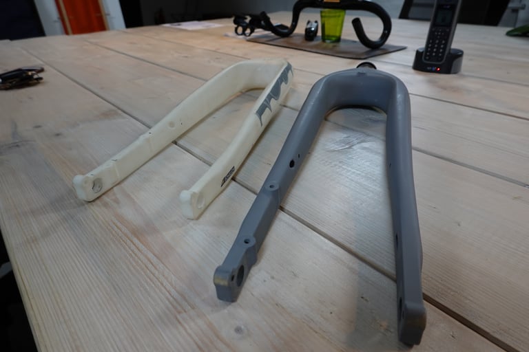 White and grey prototype versions of the Mason ISO HotShoe fork laid side by side on a wooden workshop table.