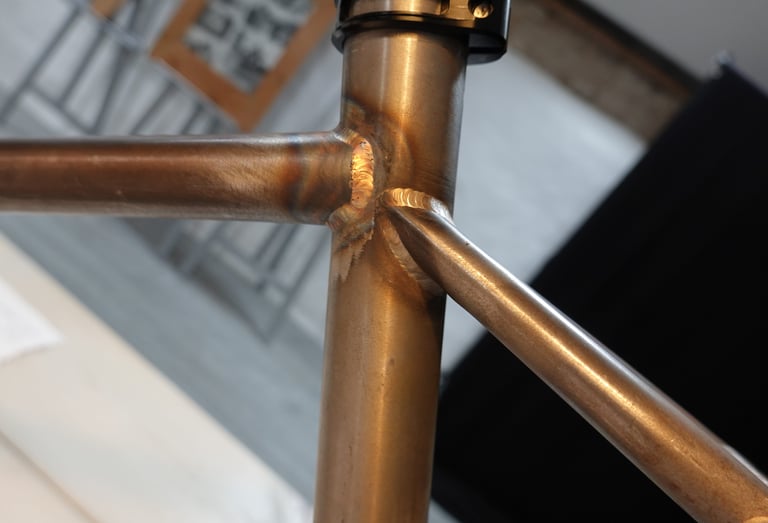 Close-up of the weld where the top tube and seatstay meet the seat tube on a bare steel Mason ISO frame.