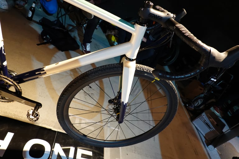 Front end of the Wish One Gravel showing the carbon fork, stem, black bar tape and front tyre.