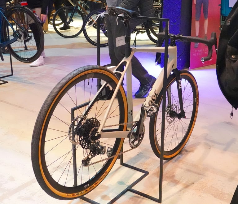 Rose Backroad carbon gravel bike in cream with tan-wall Schwalbe tyres on a display stand.