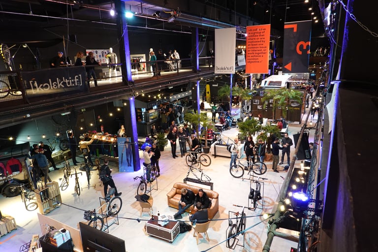 Overview from the balcony of the Kolektif Berlin Bike Fair hall, with bikes on stands and visitors below.