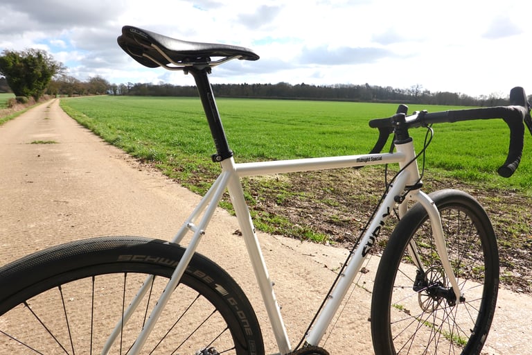 Surly Midnight Special 1x HRD top tube, saddle and Schwalbe G-One tyre beside a green field.