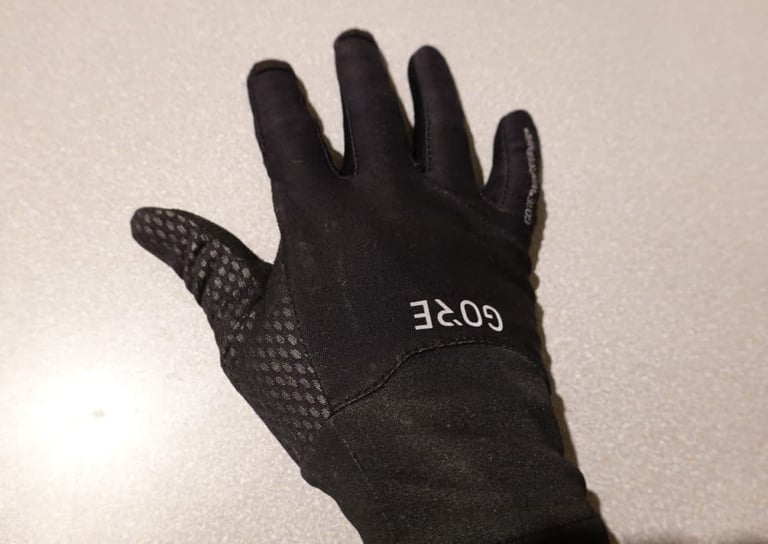 Back of a black Gore Infinium glove with the logo and a grippy dotted print on the thumb.