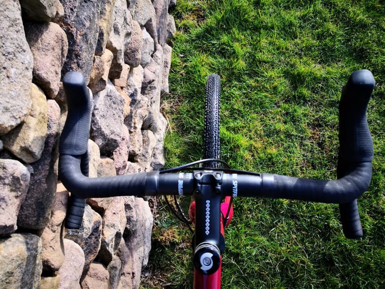 View down the Sonder Camino AL's Spitfire handlebar and stem to the front tyre, with a dry-stone wall beside it.
