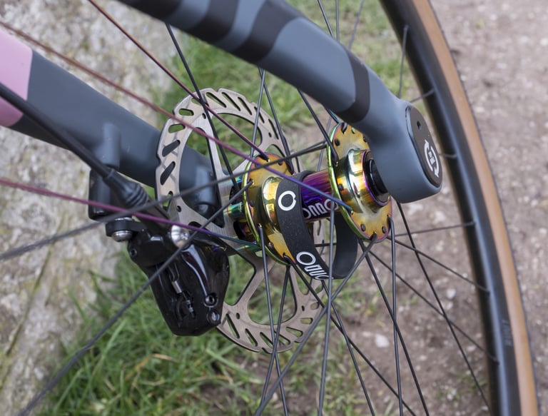 Oil-slick finish front hub on the Rondo Ruut with disc rotor and flat-mount brake caliper on the two-tone fork.