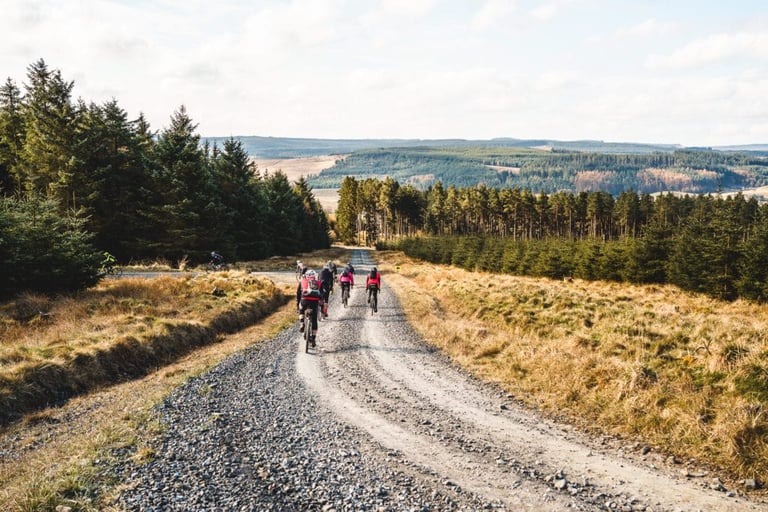 Group of riders on a long gravel forest road with views across Kielder Forest at Dirty Reiver 2019.