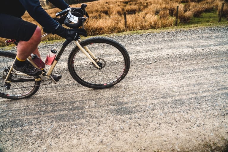 Rider with a race number on a gravel bike with knobbly tyres on a loose gravel track at Dirty Reiver 2019.