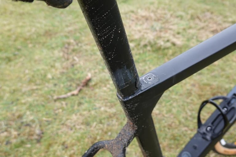 Close-up of the 3T Exploro seat post and expanding wedge clamp at the top of the seat tube, spattered with mud.