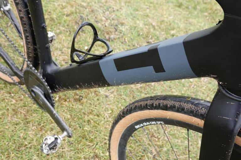 Grey and black downtube of the 3T Exploro with a black bottle cage, above the Discus Plus C25 Pro front wheel.