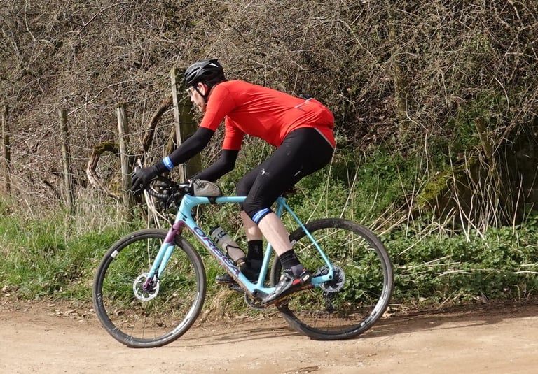 Orbea Terra M21-D 19 ridden hard along a dirt track beside a hedgerow during the review.