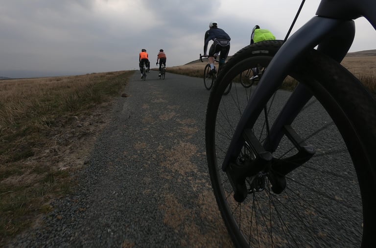 Riders on a quiet moorland road in the Yorkshire Dales during the Wahoo ELEMNT ROAM test loop, front wheel in view.