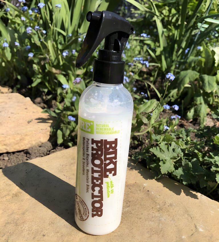 Weldtite Pure Bike Protector bottle standing upright on a stone slab among forget-me-nots.