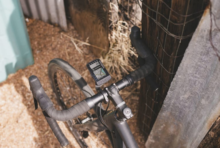 Wahoo ELEMNT ROAM mounted on a gravel bike beside a barn wall, its map screen showing the route ahead.