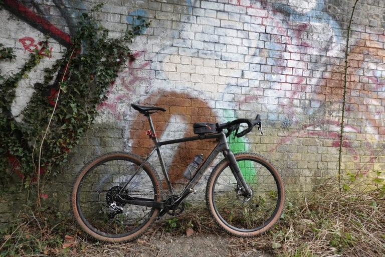 Bombtrack Hook EXT-C in 650b trim leaning against a graffiti-covered brick wall.