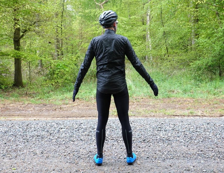 Rear view of the 7Mesh Oro jacket showing its long dropped hem, worn with arms outstretched.