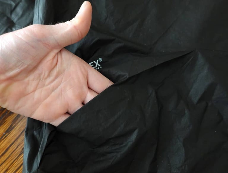 Hand reaching through the pass-through vent of the 7Mesh Oro jacket, with Gore-Tex Active branding behind.