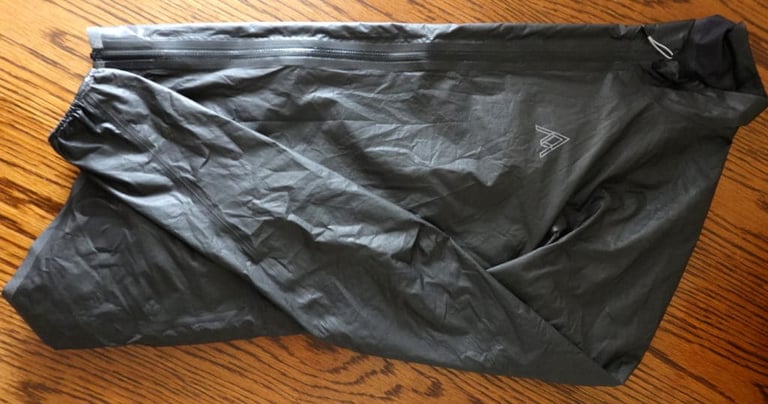 7Mesh Oro Shakedry rain jacket in black, folded flat on a wooden table.