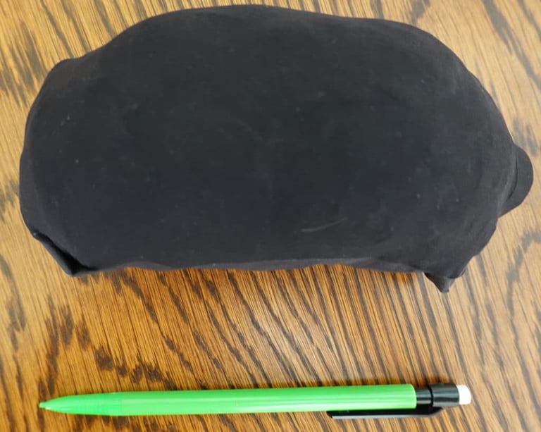 7Mesh Oro jacket stuffed into its own pocket, a small black bundle next to a pencil for scale.