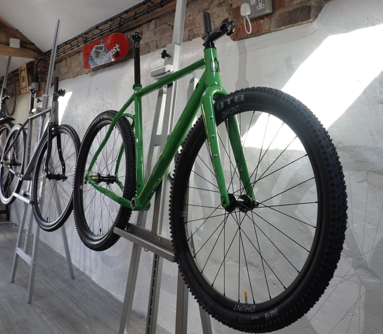 Mason Bokeh 2 in Filter Green hung on a wall rack in the showroom, with WTB Ranger 650b tyres on Hunt wheels.