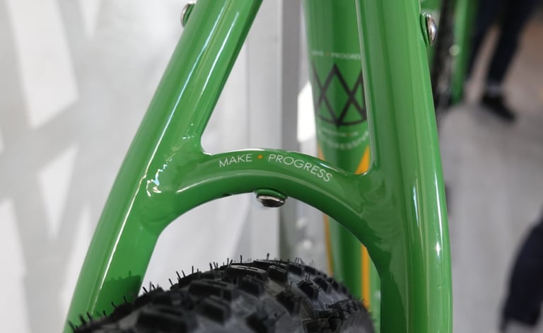 Make Progress lettering on the seatstay bridge of a green Mason Bokeh 2 frame, above a knobbly tyre.
